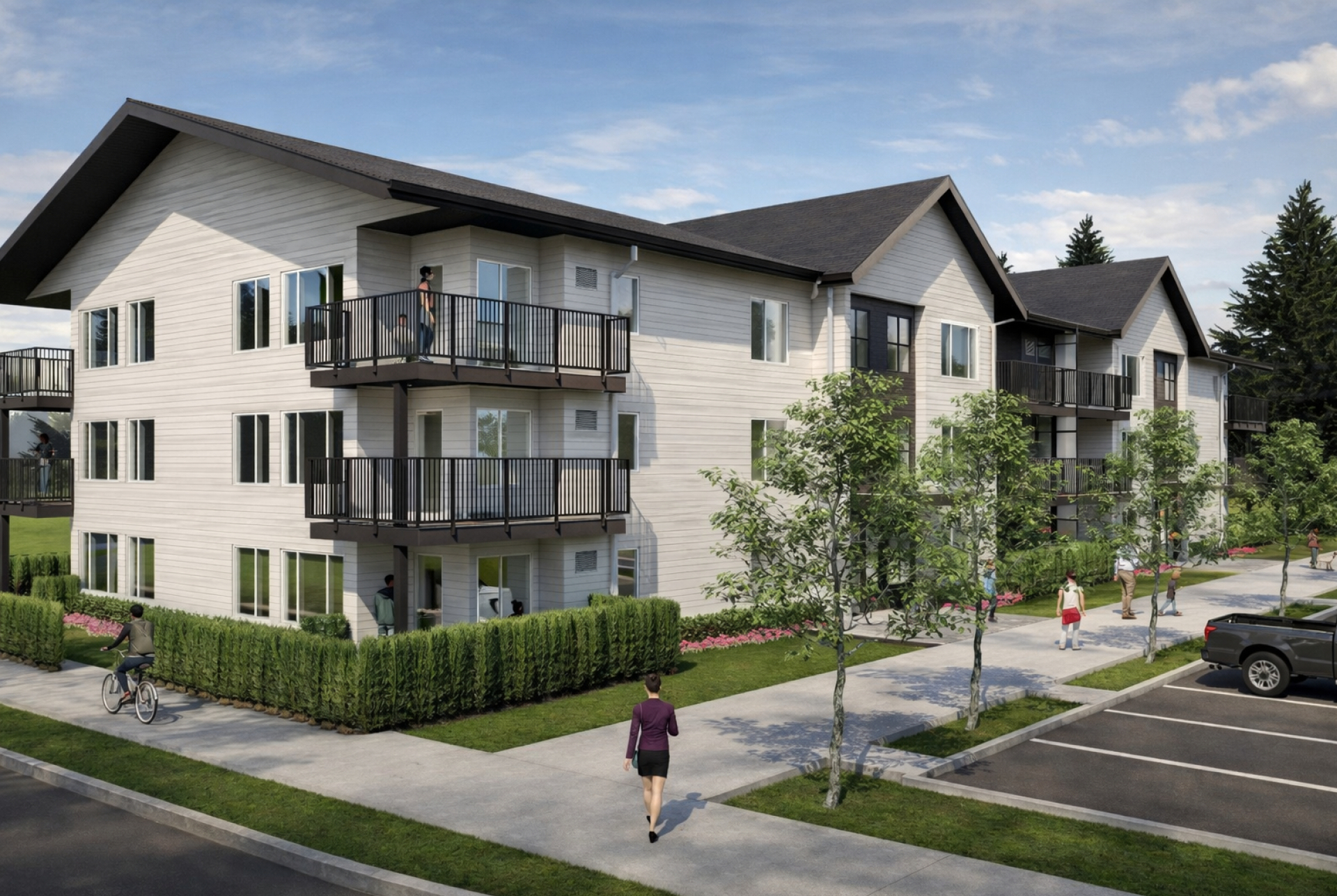 A rendered view of a three‑storey apartment building with light siding and dark roofs features multiple balconies overlooking a landscaped sidewalk. People walk and cycle along the street beside parking spaces, trees, and hedges under a clear sky.