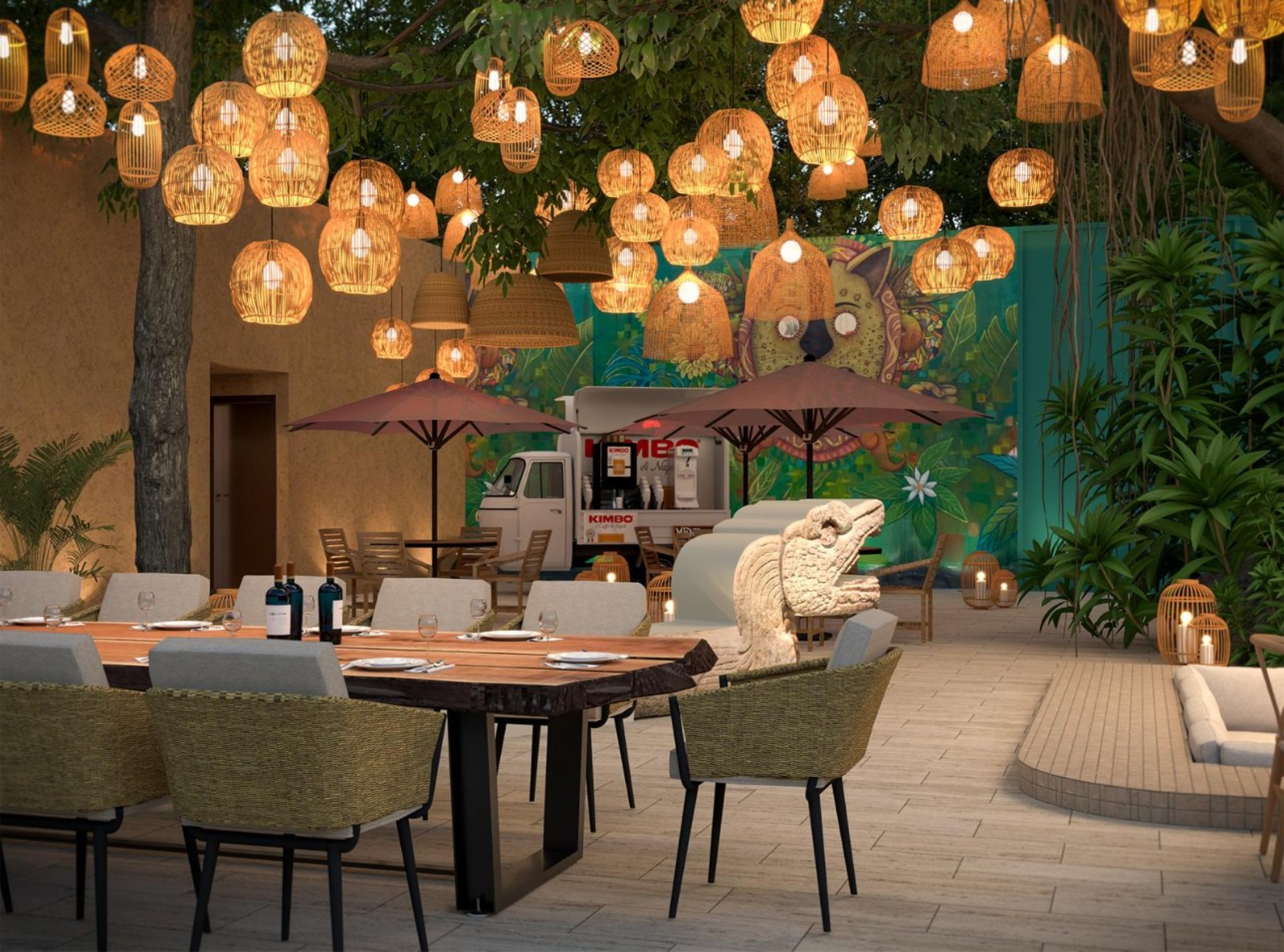 An outdoor dining area with large wood tables and woven chairs beneath hanging wicker lanterns. A colorful mural, trees, and soft ground lighting surround the tiled courtyard, creating a warm evening atmosphere.