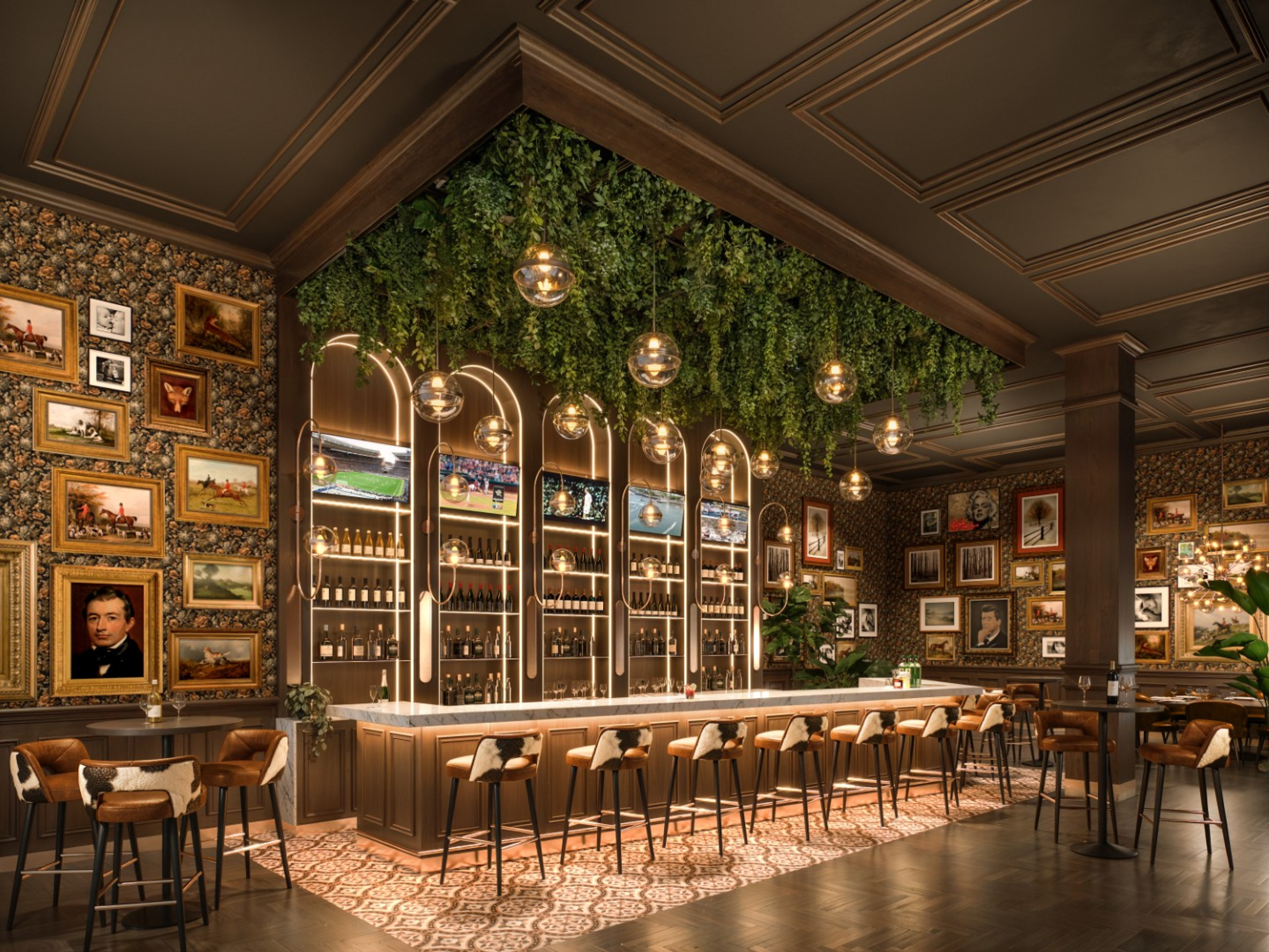 A stylish restaurant bar with a long counter lined by high stools beneath hanging greenery and globe pendant lights. Framed artwork covers the walls, and backlit shelves display bottles in a warmly lit, elegant interior.