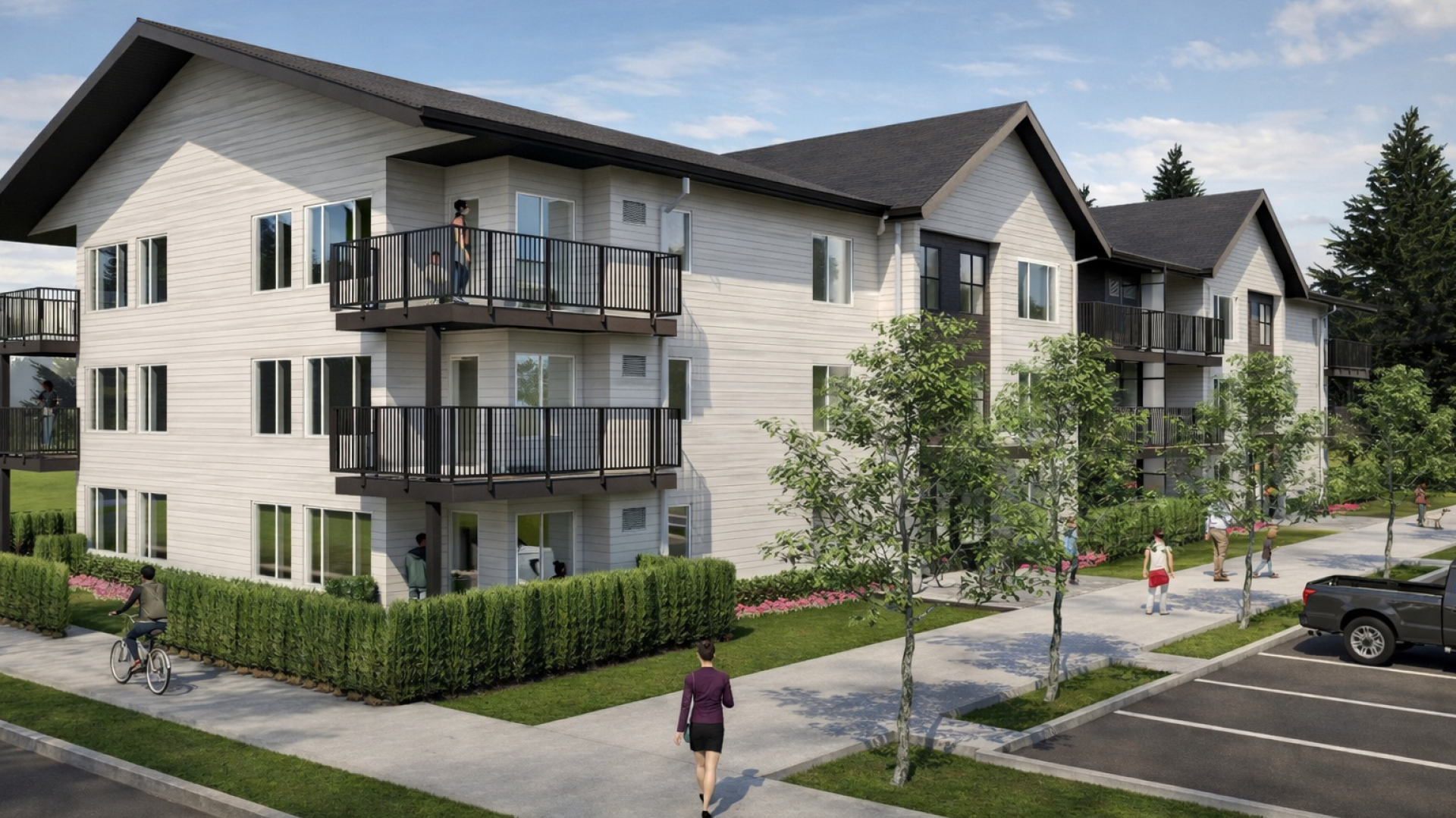 A rendered view of a three‑storey apartment building with light siding and dark roofs features multiple balconies overlooking a landscaped sidewalk. People walk and cycle along the street beside parking spaces, trees, and hedges under a clear sky.